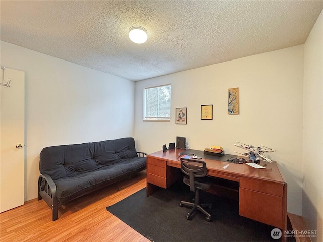 office area with light hardwood / wood-style floors and a textured ceiling