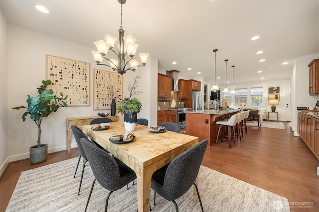 dining space featuring sink, a notable chandelier, and light hardwood / wood-style floors