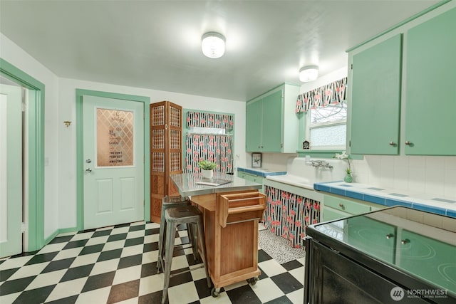 kitchen featuring green cabinets, dark floors, a kitchen bar, black electric range oven, and a sink