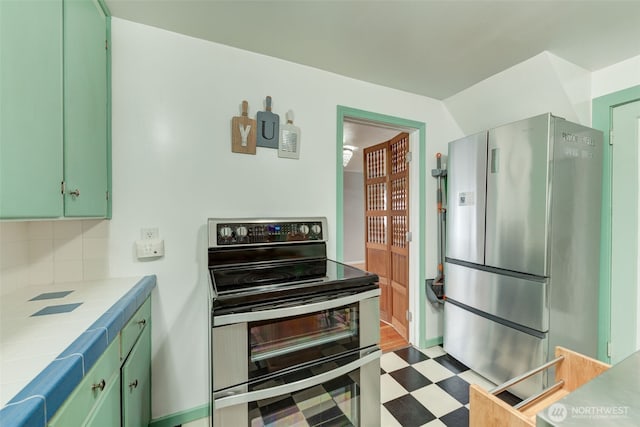 kitchen with tile countertops, light floors, appliances with stainless steel finishes, and green cabinets