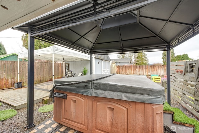 view of patio / terrace with a gazebo, a deck, a hot tub, and a fenced backyard