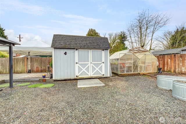 view of greenhouse with a storage shed and a fenced backyard