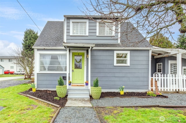 bungalow-style home featuring roof with shingles and fence