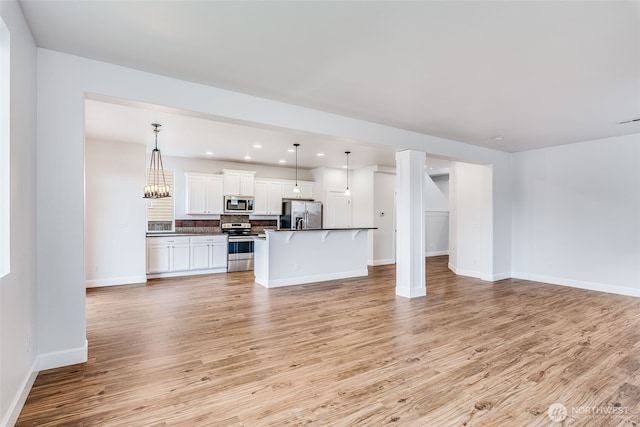 unfurnished living room featuring recessed lighting, a chandelier, baseboards, and light wood-style flooring