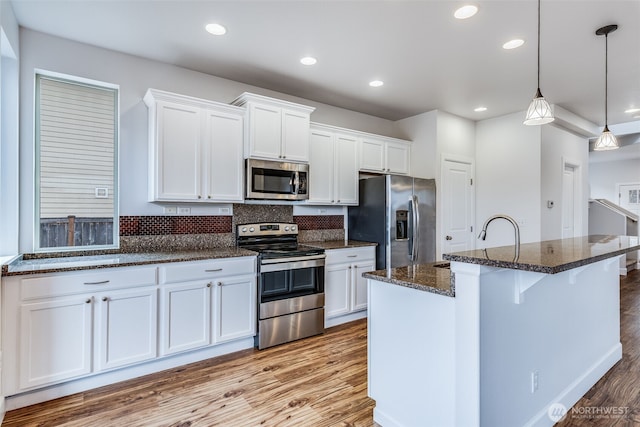 kitchen with backsplash, white cabinetry, stainless steel appliances, and wood finished floors