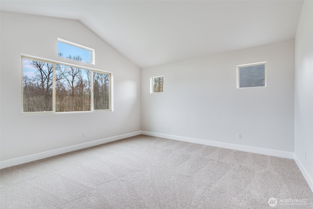 spare room with vaulted ceiling, baseboards, and carpet floors