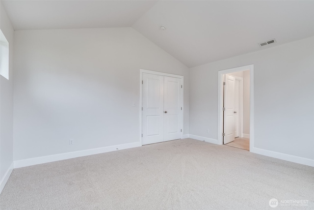 spare room featuring visible vents, baseboards, light colored carpet, and vaulted ceiling