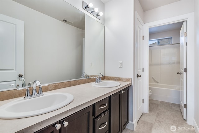 full bathroom with a sink, visible vents, toilet, and double vanity