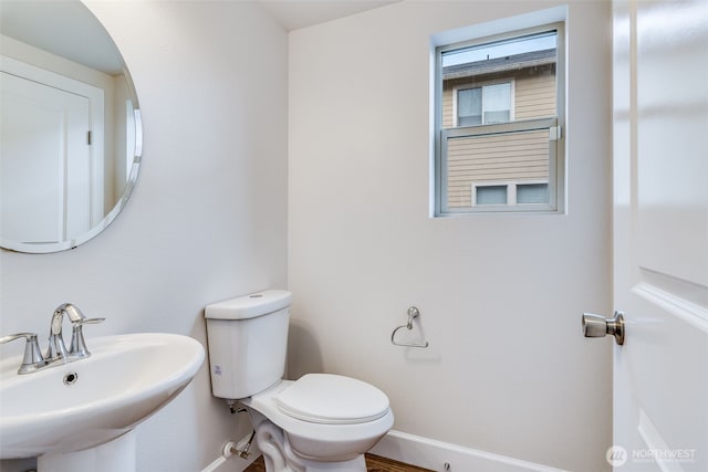 bathroom featuring toilet, baseboards, and a sink