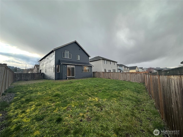 rear view of house with a yard and a fenced backyard