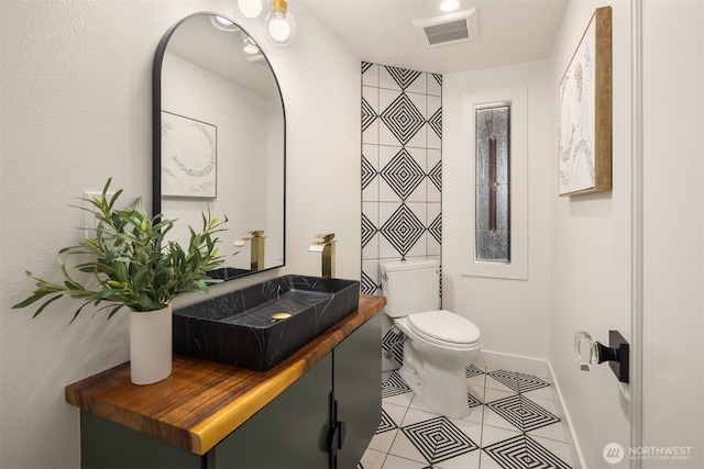 bathroom featuring visible vents, toilet, a sink, tile patterned flooring, and baseboards