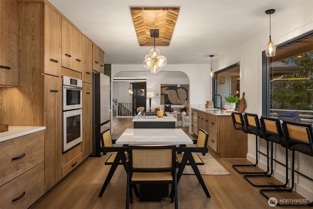 kitchen with light countertops, brown cabinetry, and pendant lighting