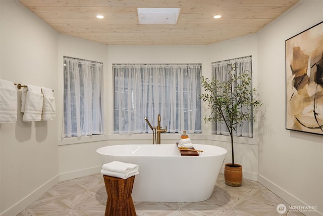 bathroom with a freestanding bath, a skylight, baseboards, and recessed lighting