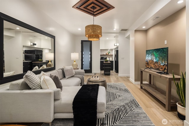 living room featuring light wood-style floors, recessed lighting, visible vents, and baseboards