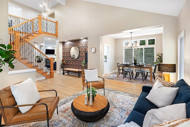 living room featuring light wood-type flooring, high vaulted ceiling, and a notable chandelier