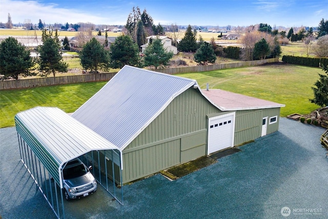 exterior space featuring a rural view, a garage, and a lawn