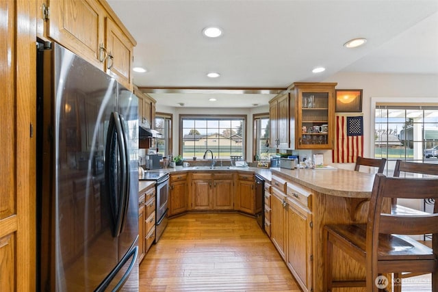 kitchen featuring kitchen peninsula, stainless steel appliances, a wealth of natural light, sink, and a kitchen breakfast bar