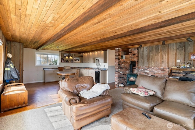 living room with sink, a wood stove, light hardwood / wood-style floors, and wood ceiling