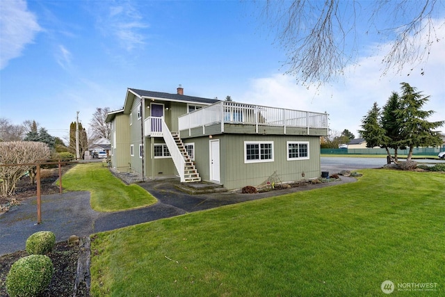 rear view of property with a wooden deck and a lawn