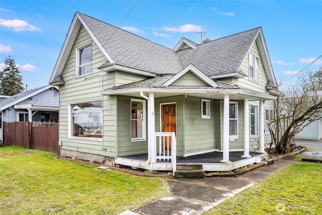 bungalow-style home with a shingled roof, fence, a front lawn, and a porch