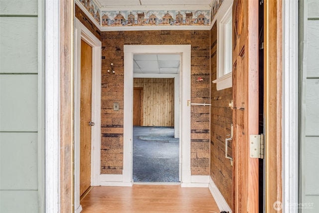 hallway featuring light wood finished floors and wood walls