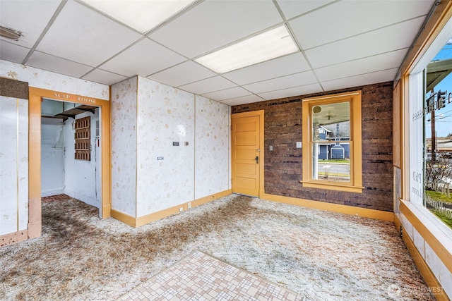 carpeted spare room featuring a paneled ceiling, plenty of natural light, and baseboards