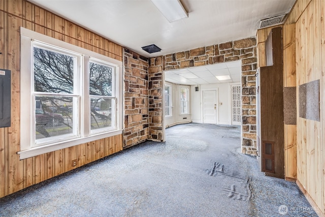 unfurnished room featuring carpet floors, electric panel, visible vents, and wooden walls