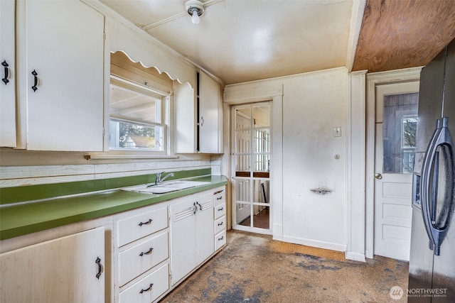 kitchen featuring concrete flooring, white cabinetry, and a sink