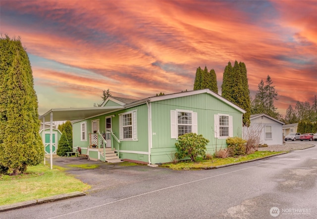 manufactured / mobile home featuring an attached carport, crawl space, an outdoor structure, and driveway