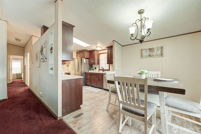 kitchen with stainless steel appliances, light countertops, visible vents, an inviting chandelier, and a textured ceiling