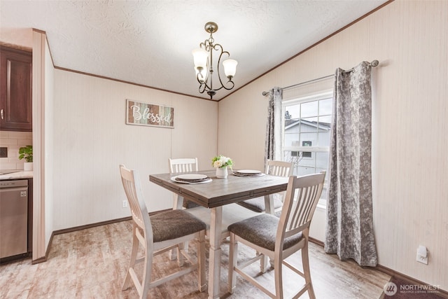 dining area featuring light wood-style floors, crown molding, vaulted ceiling, and a notable chandelier