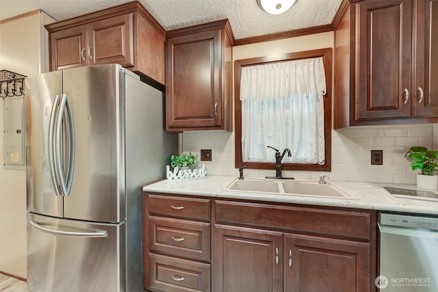 kitchen featuring stainless steel appliances, light stone countertops, a sink, and tasteful backsplash