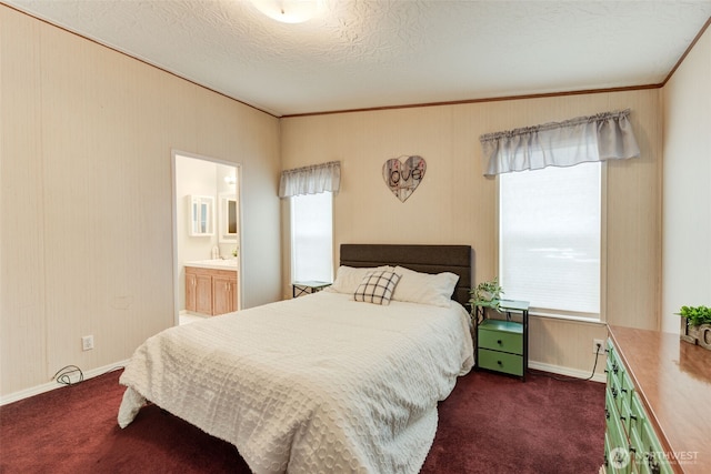 bedroom with a textured ceiling, dark colored carpet, a sink, and ensuite bathroom