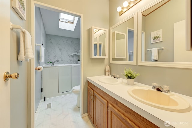 bathroom featuring visible vents, a skylight, a sink, and a shower with shower door