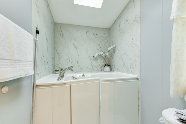 full bath with a skylight, a garden tub, and toilet