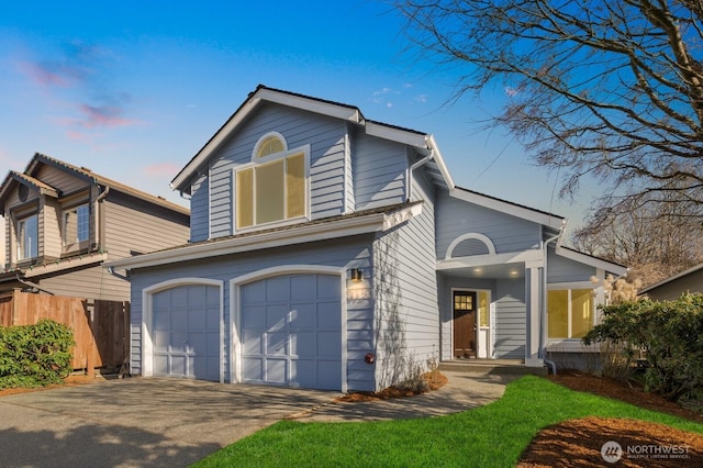 traditional-style home with a garage, driveway, and fence