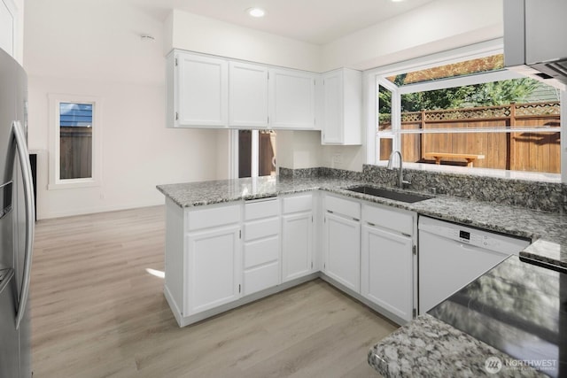 kitchen with white cabinets, stainless steel fridge with ice dispenser, light stone countertops, white dishwasher, and a sink