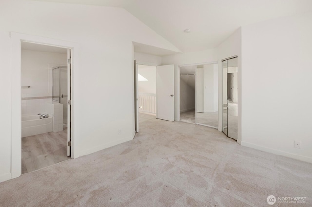 unfurnished bedroom featuring baseboards, vaulted ceiling, carpet flooring, and ensuite bathroom