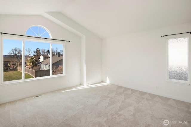 spare room with carpet floors, visible vents, vaulted ceiling, and baseboards