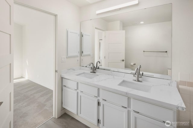 bathroom with a sink, toilet, and double vanity