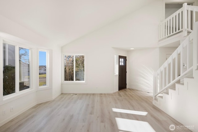 foyer entrance with high vaulted ceiling, stairway, wood finished floors, and baseboards