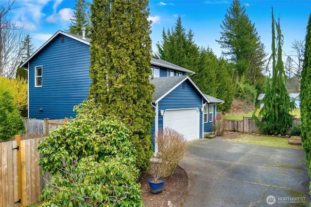 exterior space featuring a garage, fence, and aphalt driveway