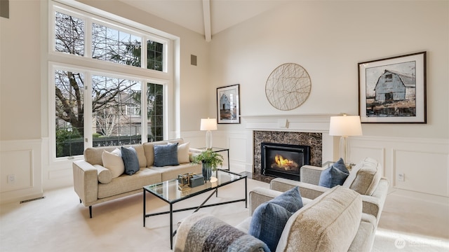 living area with a high end fireplace, a wainscoted wall, and a decorative wall