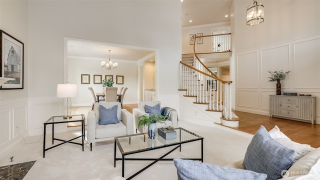 living area with stairway, a decorative wall, a notable chandelier, and ornamental molding