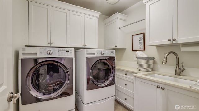 clothes washing area with washer and clothes dryer, a sink, and cabinet space