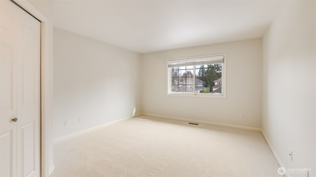 empty room featuring baseboards, visible vents, and light colored carpet