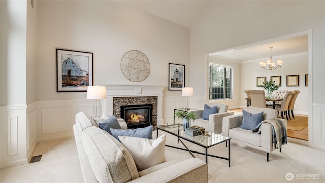 living room featuring a chandelier, crown molding, a premium fireplace, and a decorative wall