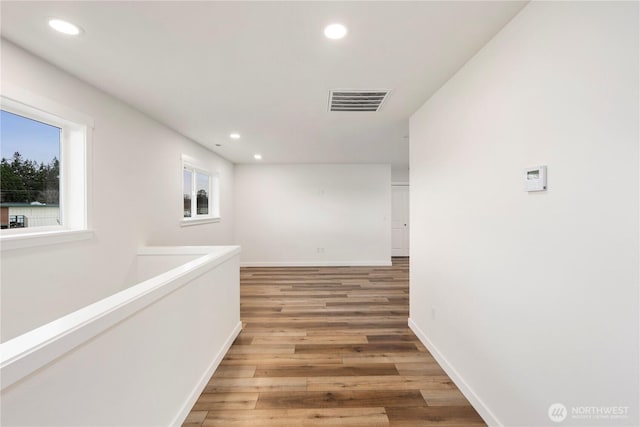corridor featuring light wood finished floors, visible vents, recessed lighting, and a healthy amount of sunlight