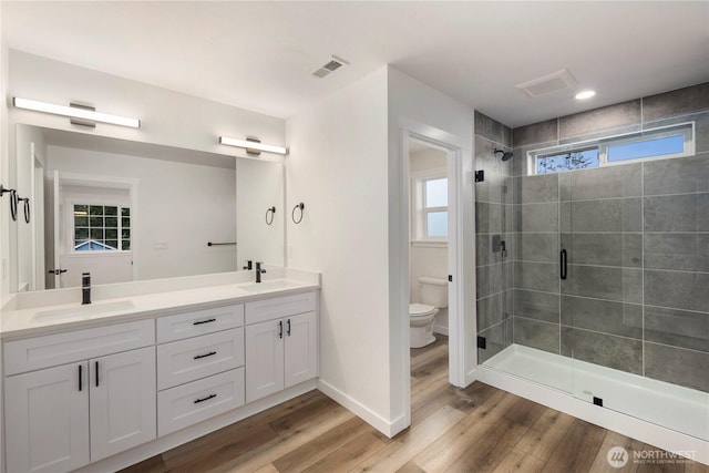 full bath with a shower stall, toilet, visible vents, and a sink
