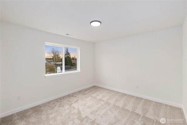 unfurnished room with visible vents, baseboards, and light colored carpet